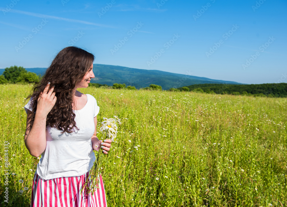 夏日草地上戴着雏菊的年轻深色女人