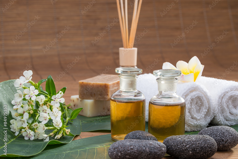 Essential Oil, flower, pebble stone on green leaf, white towel,