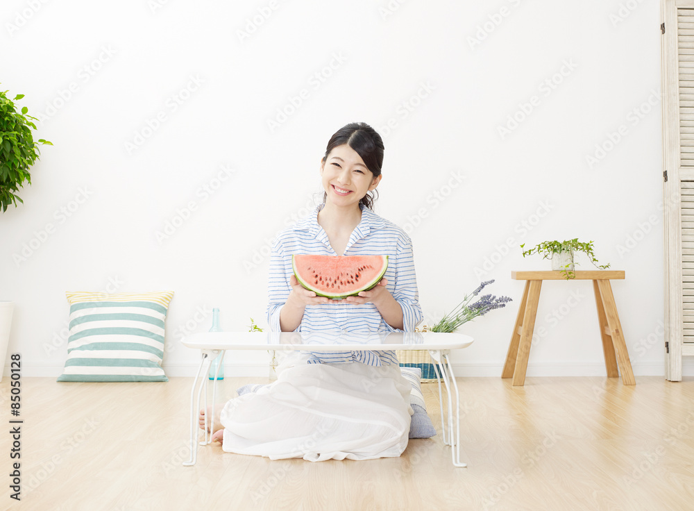 部屋で西瓜を食べる女性