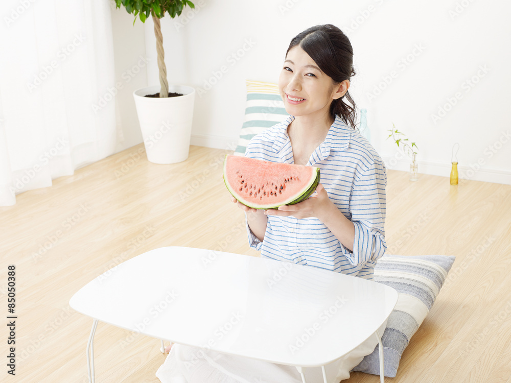 部屋で西瓜を食べる女性