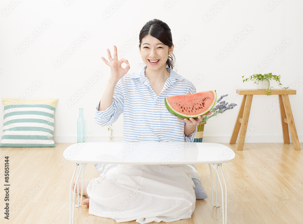 部屋で西瓜を食べる女性　OKサイン