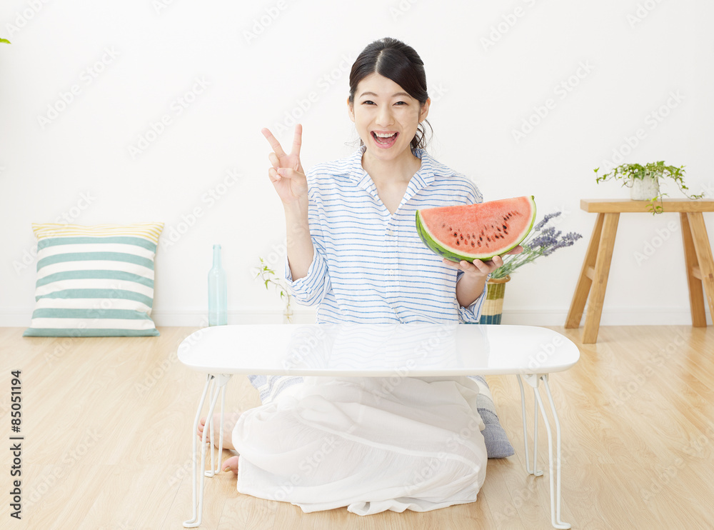 部屋で西瓜を食べる女性　ピースサイン