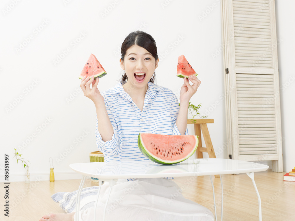 部屋で西瓜を食べる女性