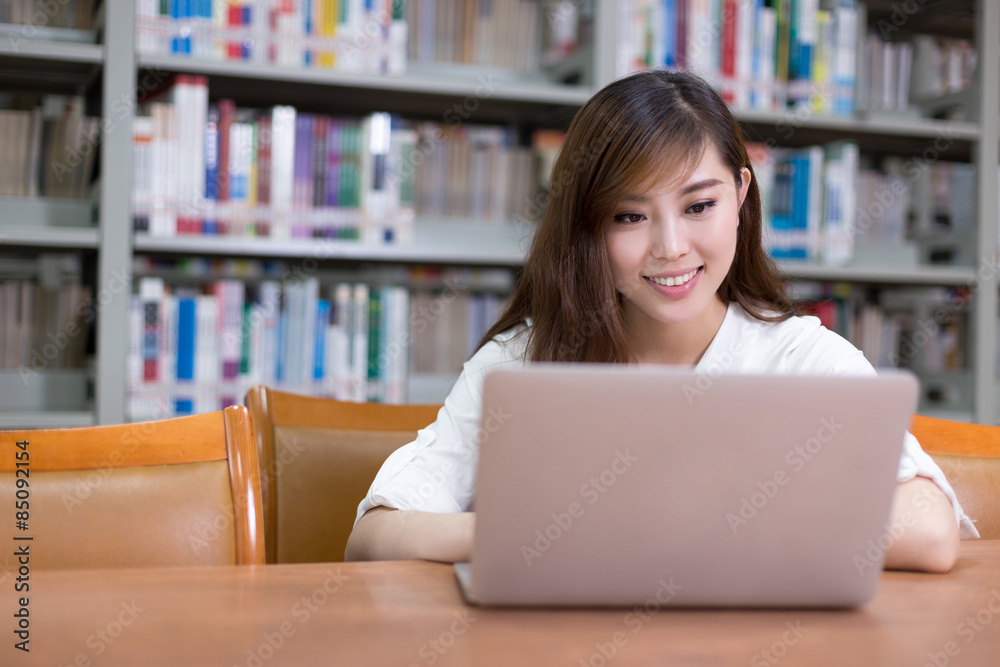 Beautiful asian female student using laptop for study in library