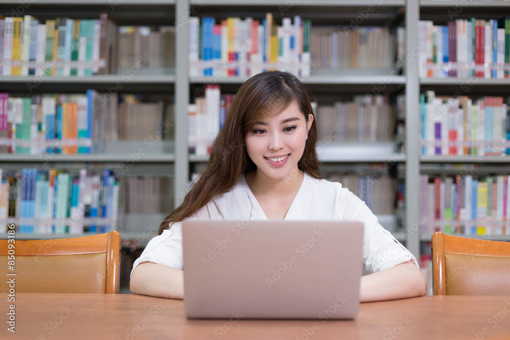 Beautiful asian female student using laptop for study in library