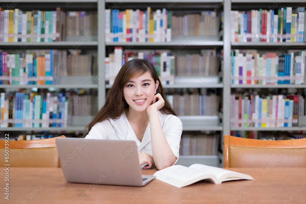 Beautiful asian female student using laptop for study in library