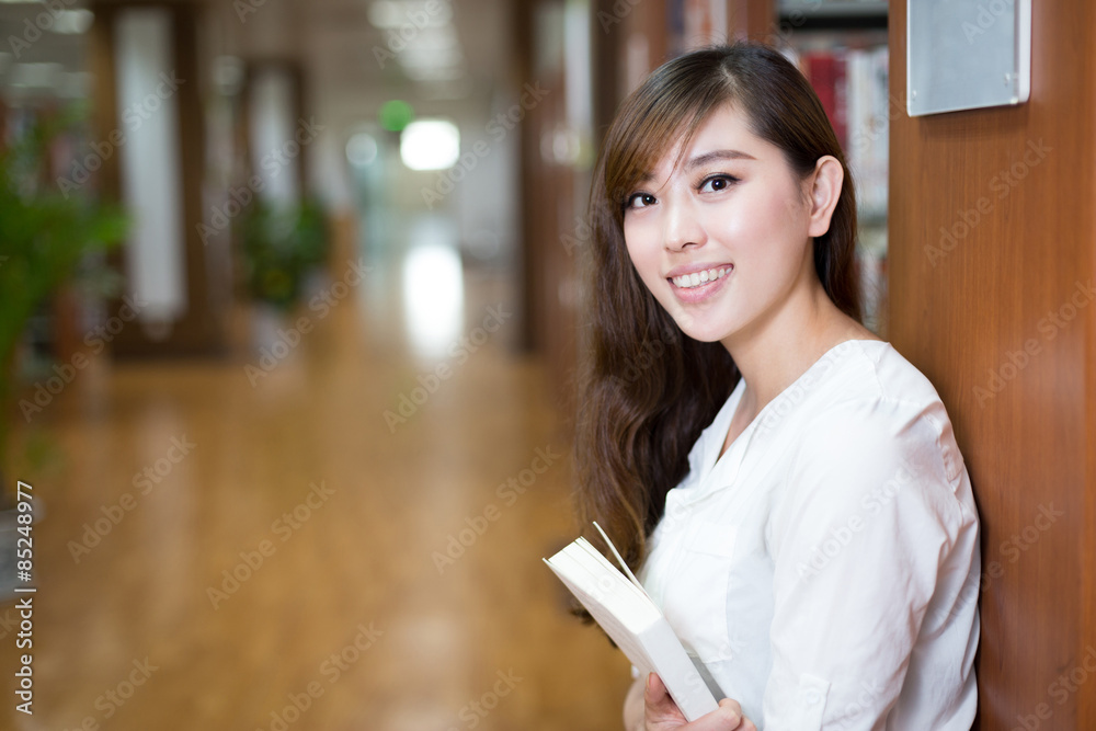 亚洲漂亮的女学生在图书馆里拿着书