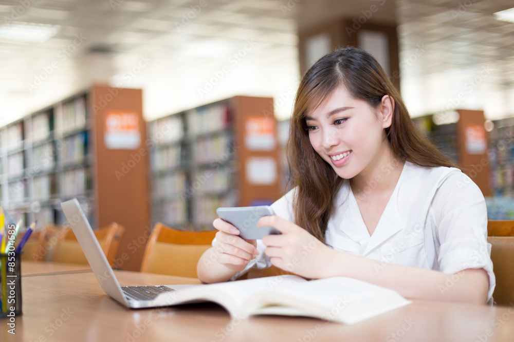 亚洲美女女学生在图书馆使用手机