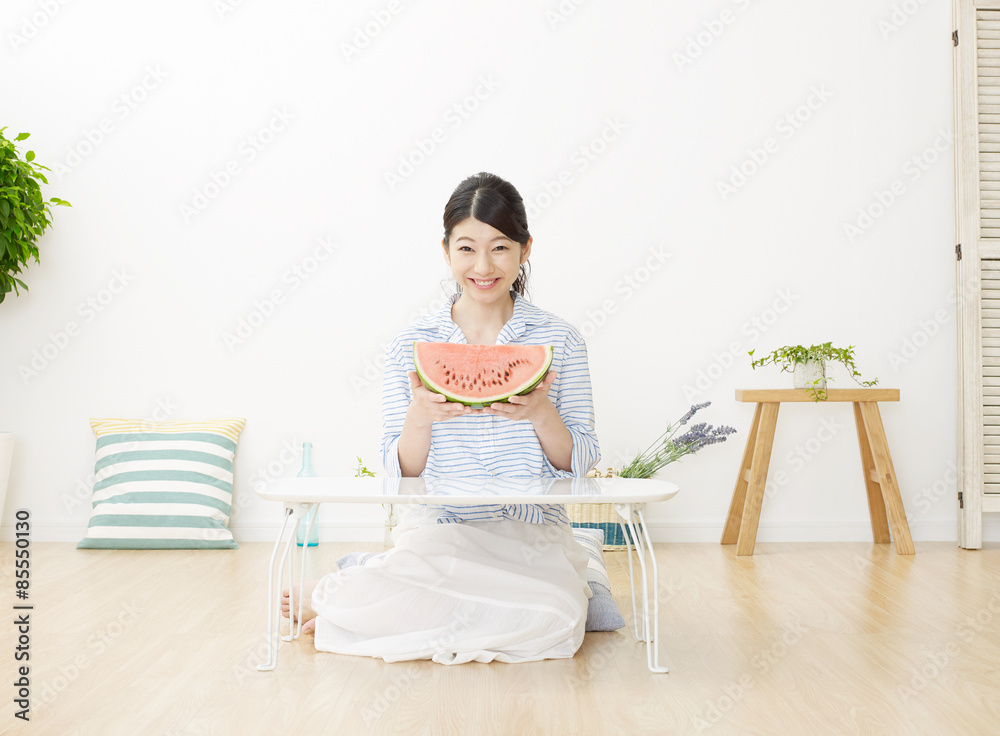 部屋で西瓜を食べる女性