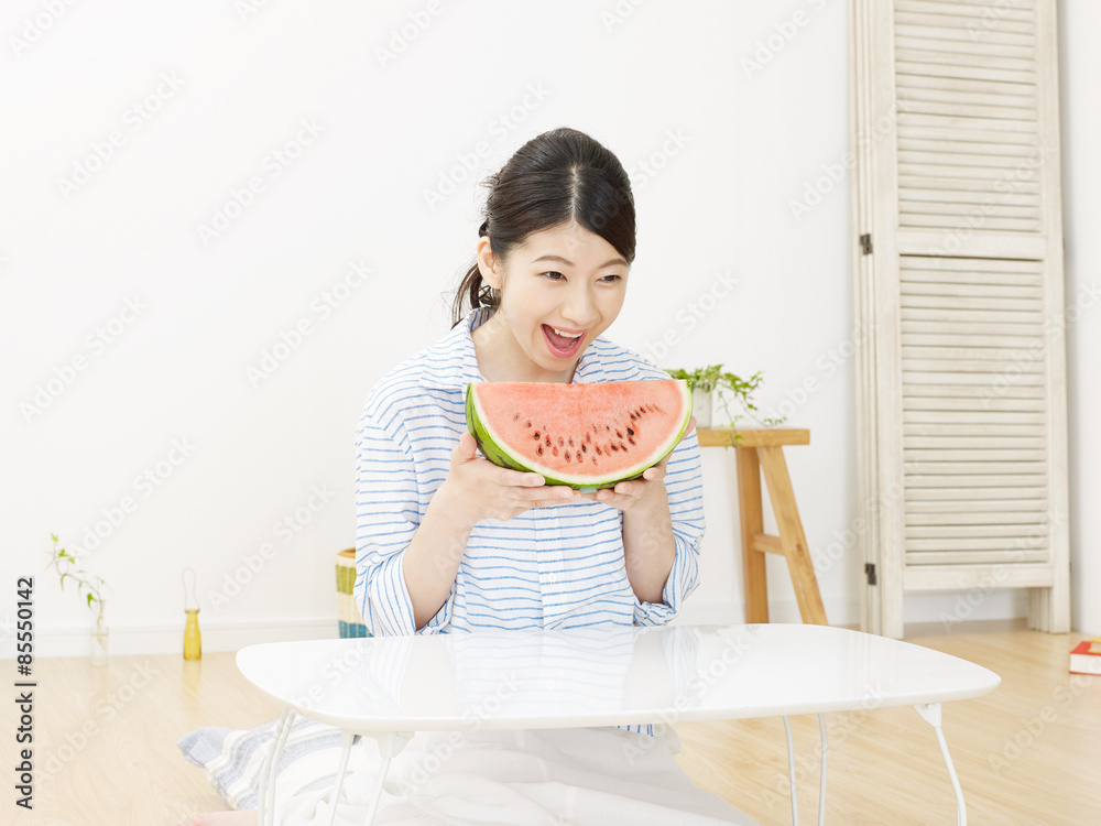 部屋で西瓜を食べる女性