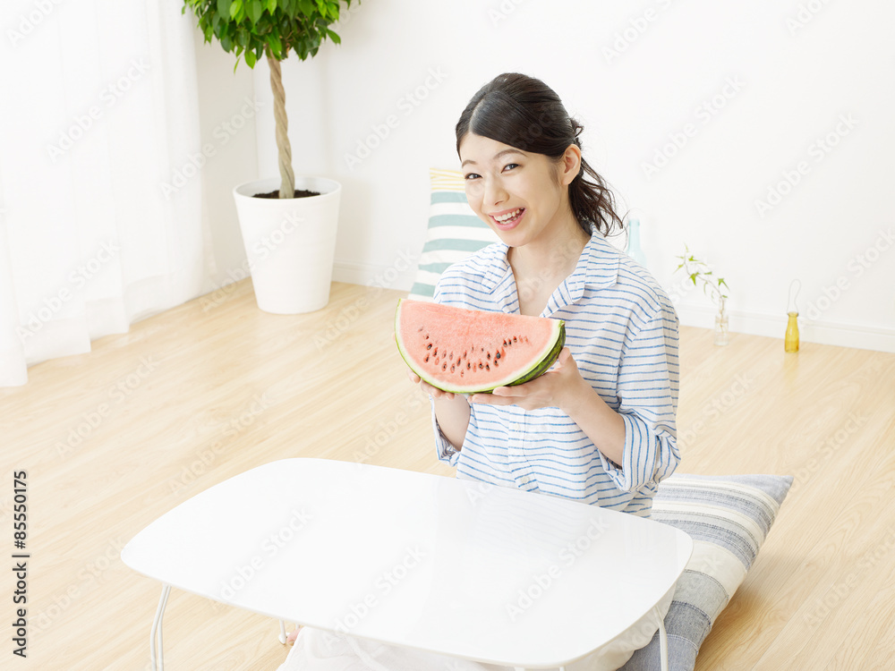 部屋で西瓜を食べる女性