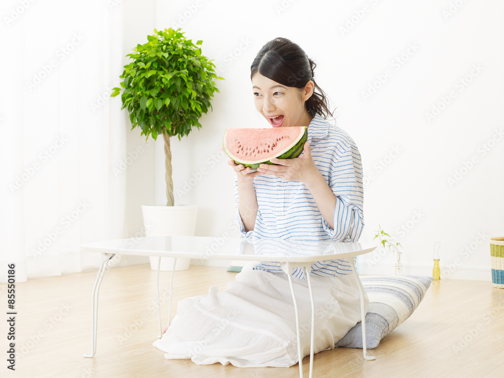 部屋で西瓜を食べる女性