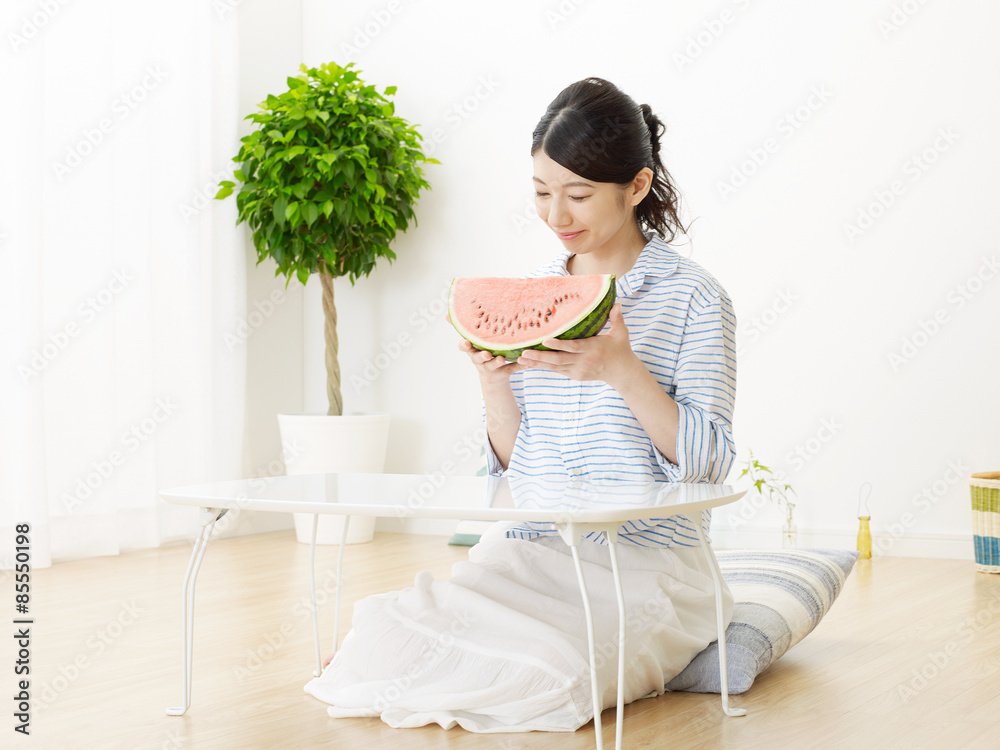 部屋で西瓜を食べる女性