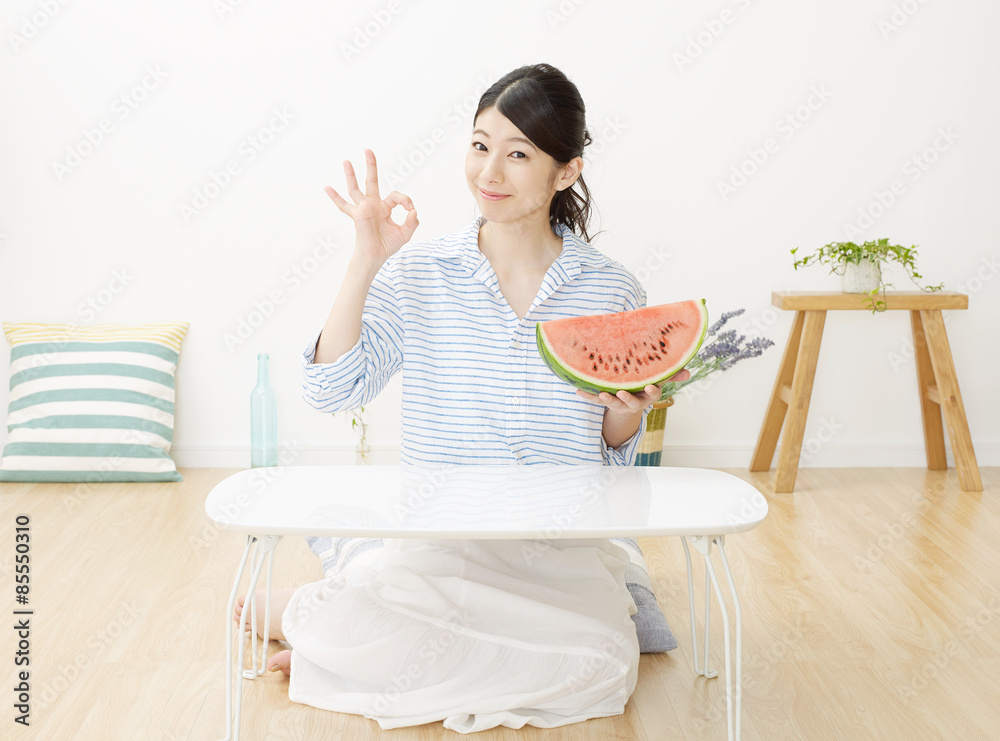 部屋で西瓜を食べる女性　OKサイン