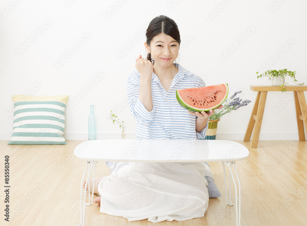 部屋で西瓜を食べる女性　ガッツポーズ