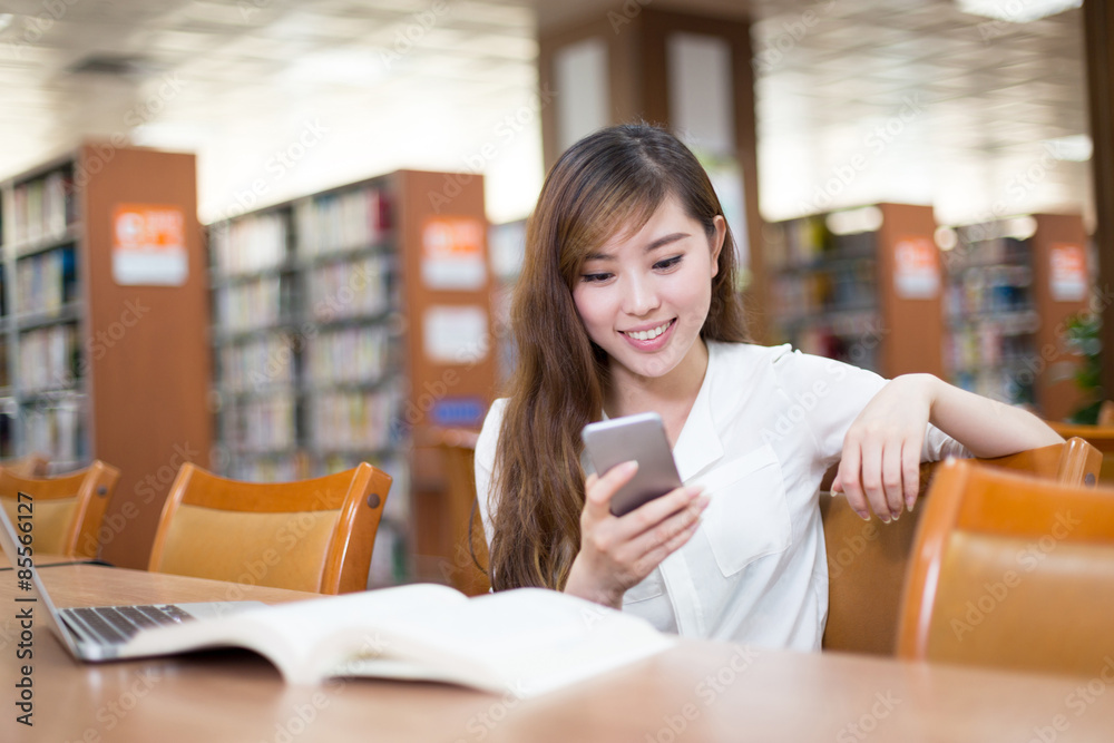 亚洲美女女学生在图书馆使用手机