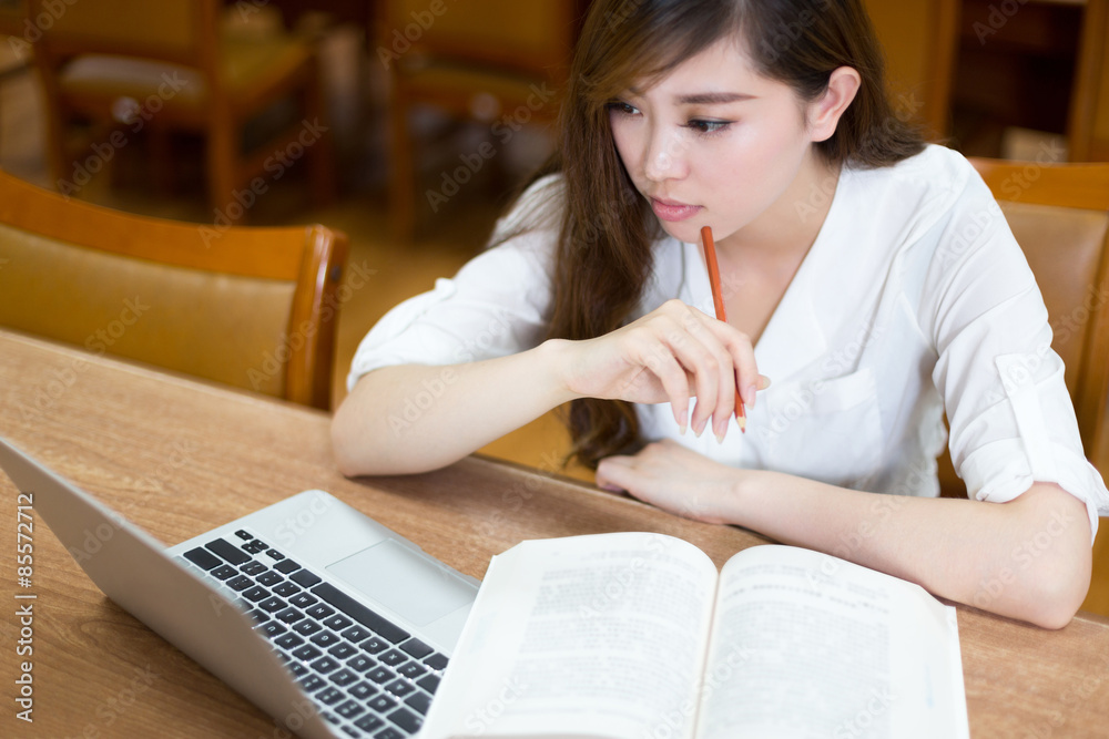 亚洲美女女学生在图书馆用笔记本电脑学习