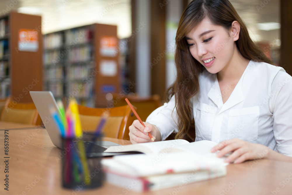 亚洲美女女学生在图书馆用笔记本电脑学习