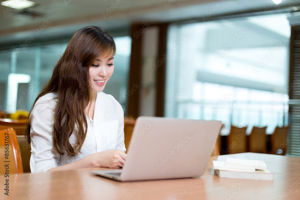 亚洲美女女学生在图书馆用笔记本电脑学习