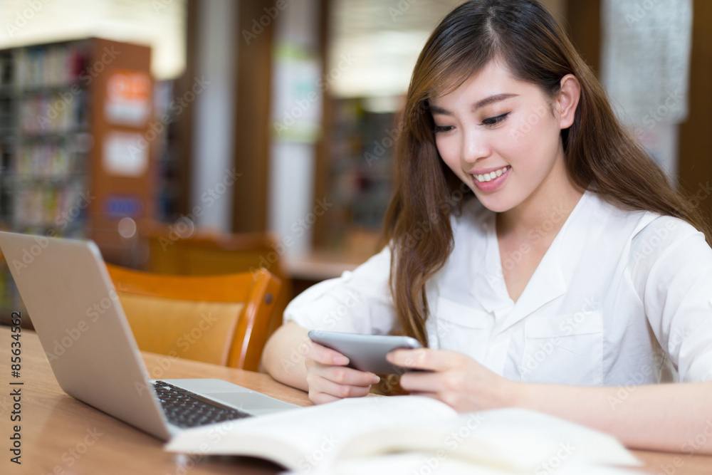 亚洲美女女学生在图书馆用笔记本电脑学习