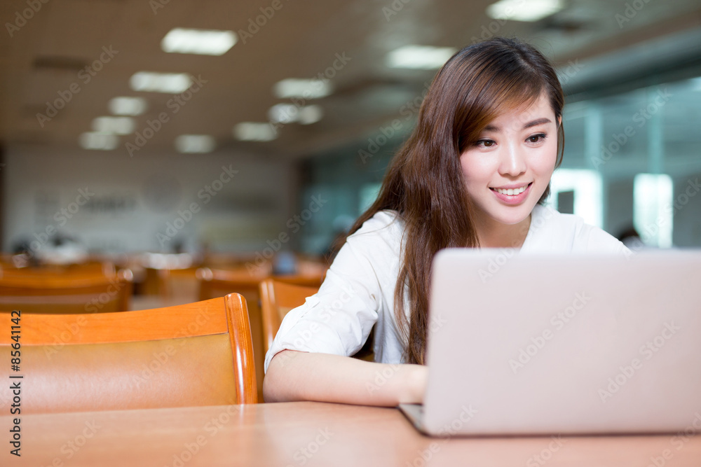 Asian beautiful female student study in library with laptop