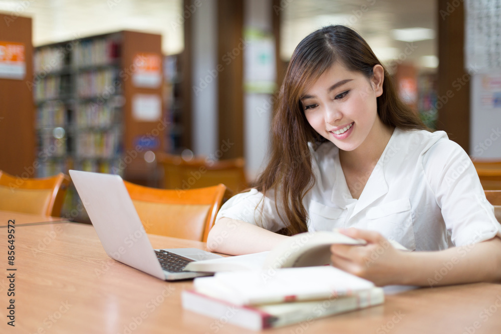 Asian beautiful female student study in library with laptop