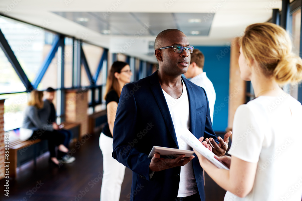 Black executive talking to white female colleague