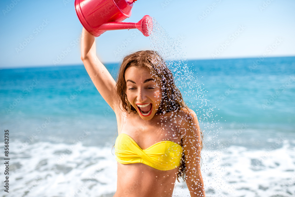 Woman pouring water from watering can on the beach