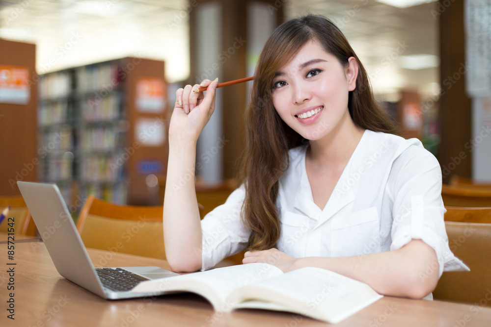 亚洲美女女学生在图书馆用笔记本电脑学习