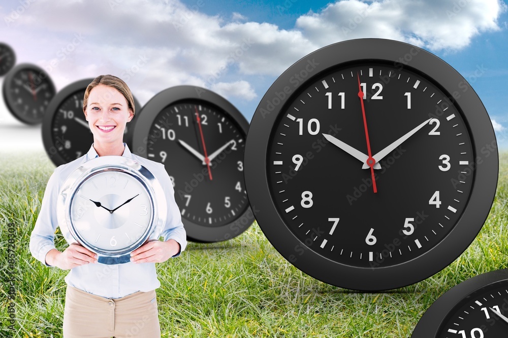 Composite image of businesswoman in suit holding a clock