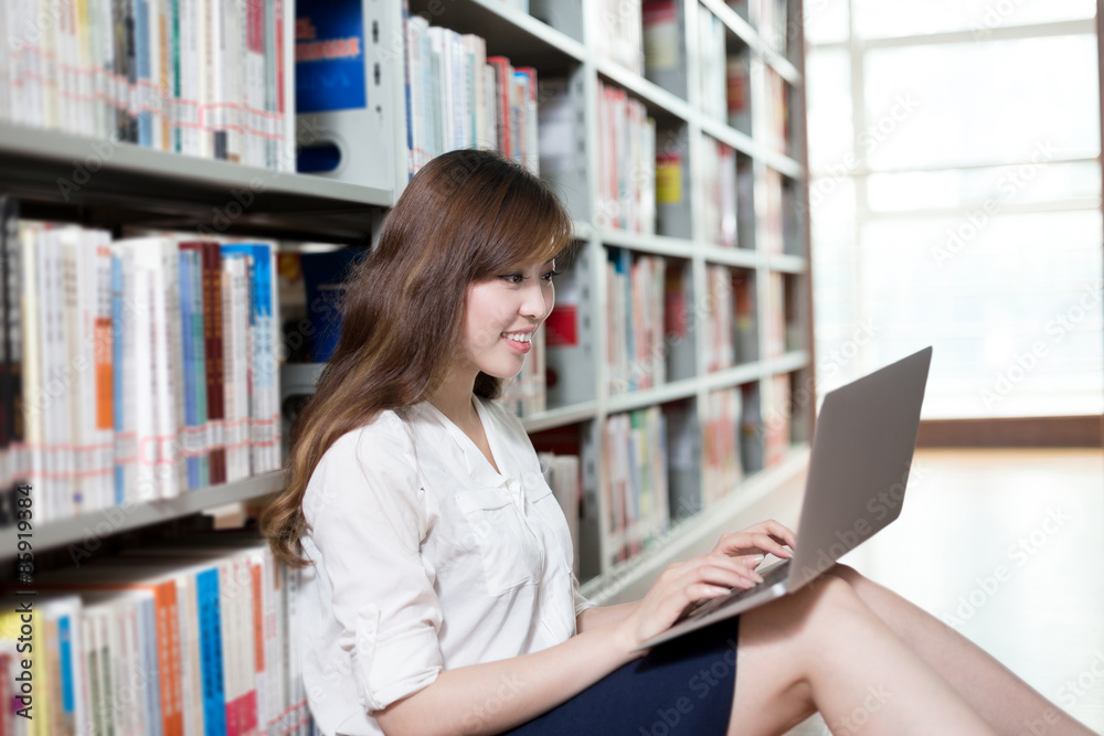 Asian beautiful female student studying in library with laptop