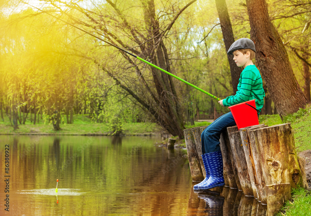 Boy sitting, looking at water and fishing on pond