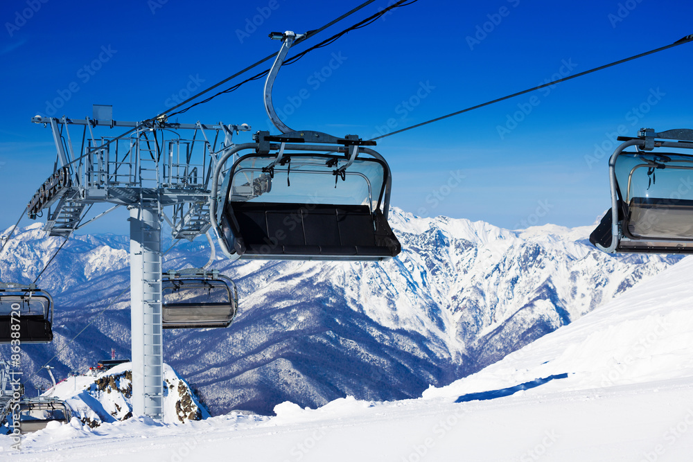 Chairs on chairlift ropeway in winter mountains