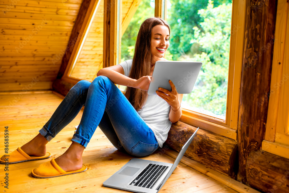 Woman with tablet near the window in cottage