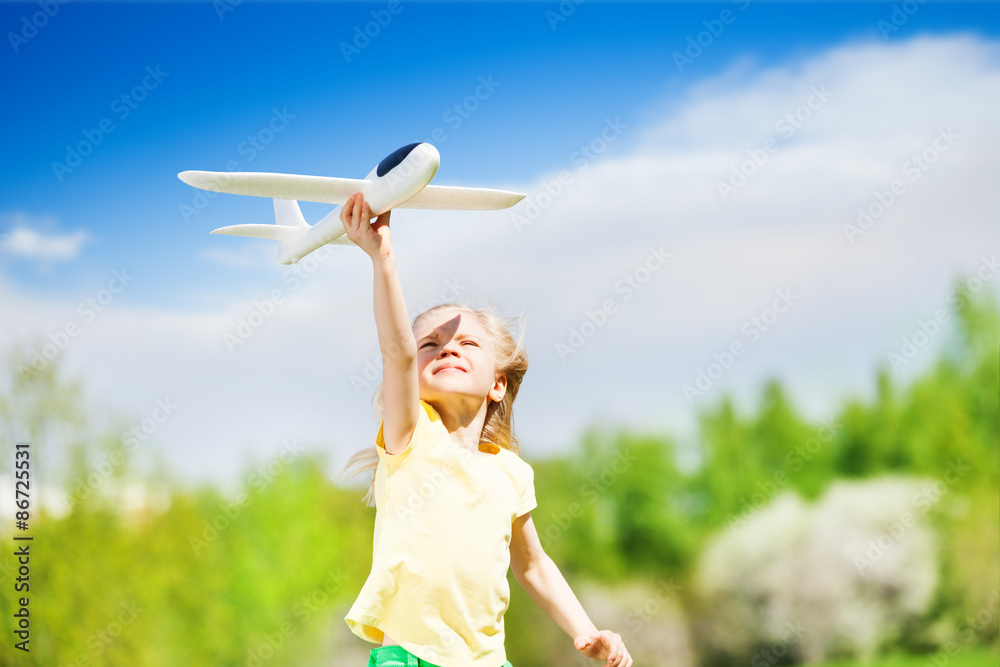 Portrait of happy blond girl holding airplane toy