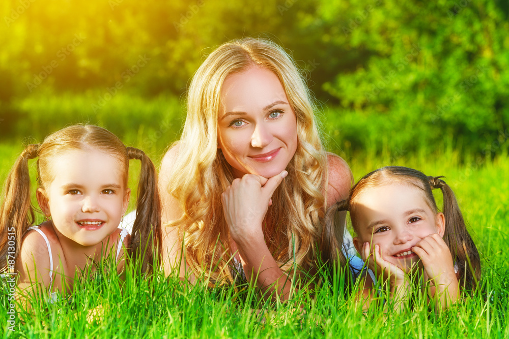 happy family mother and children twin sisters on meadow in summe