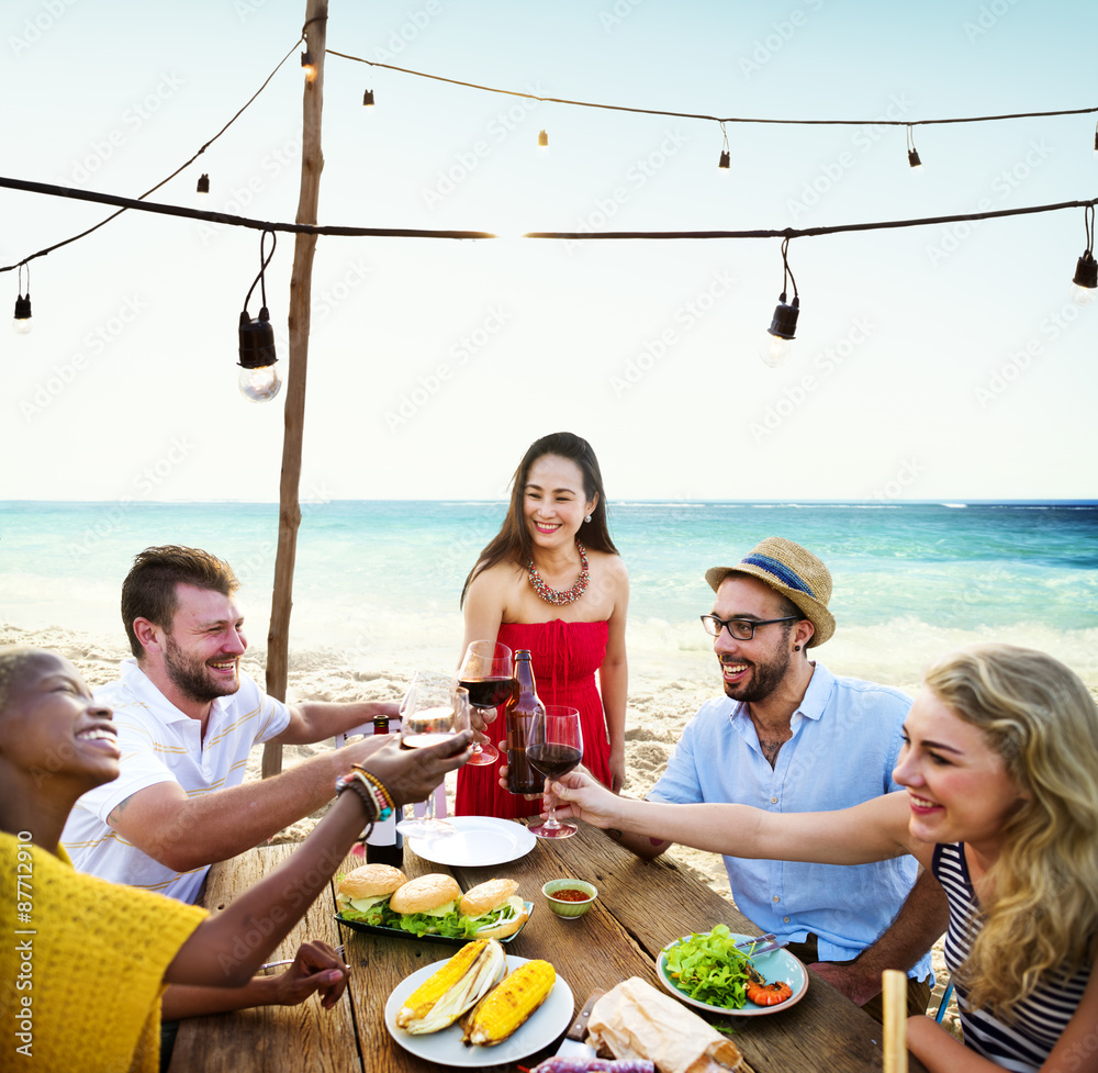 朋友们在夏季海滩聚会上用餐愉快的概念