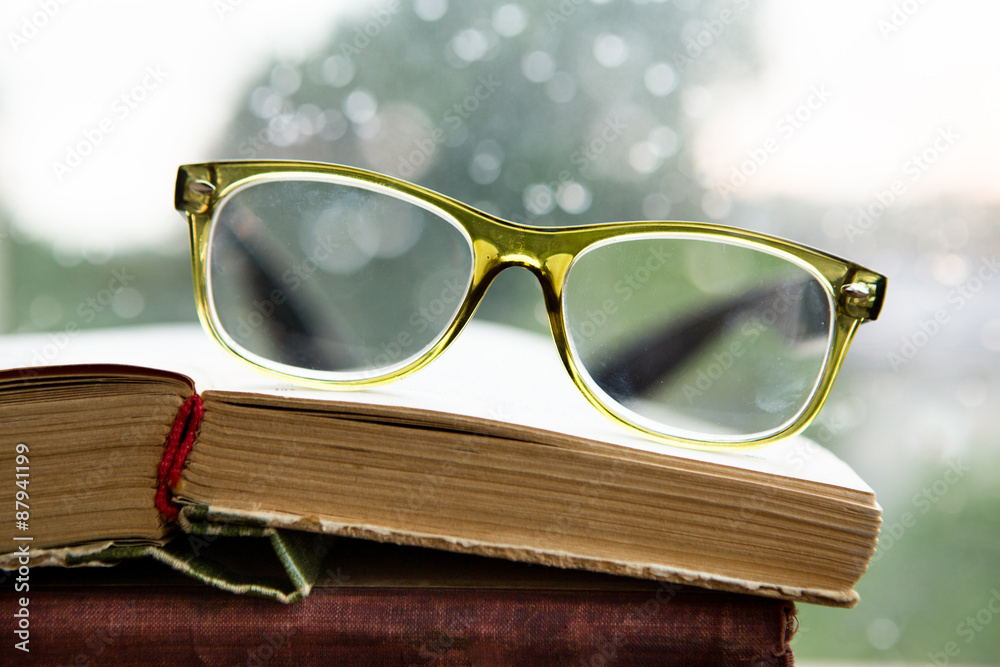 Reading glasses and book on rainy window