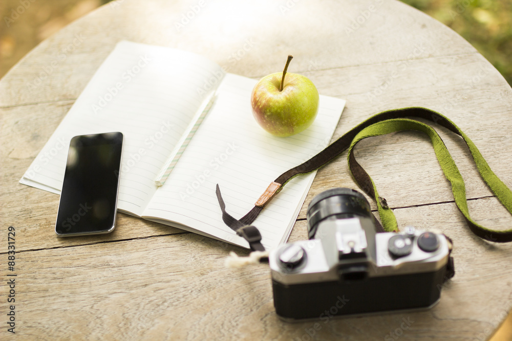 cell phone, diary, old camera and green apple