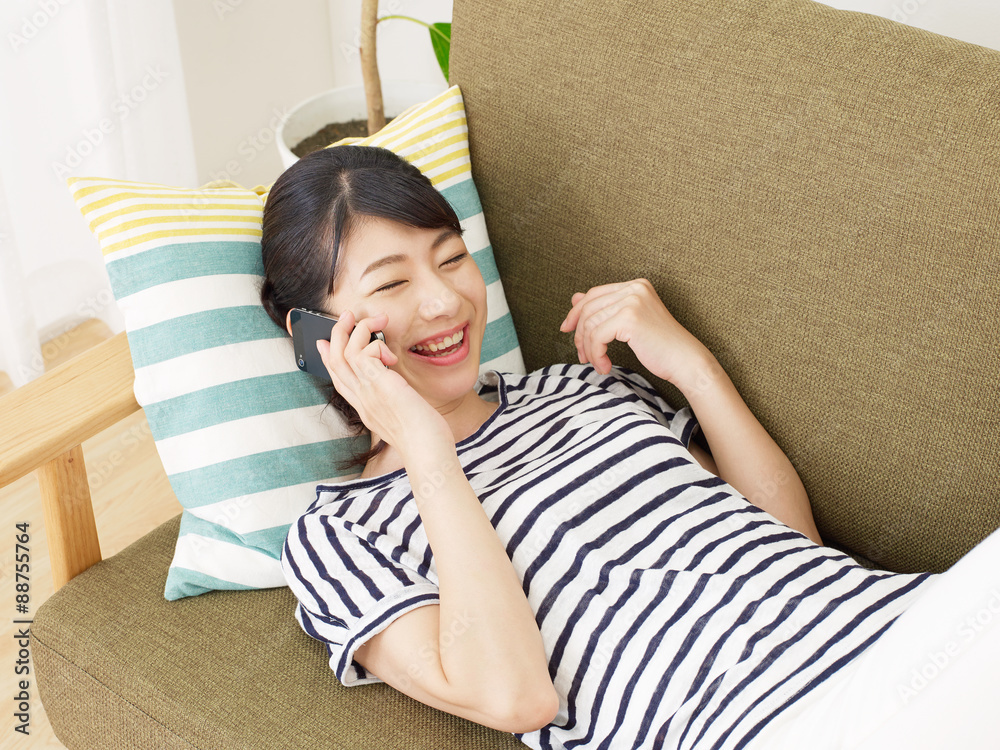 部屋でスマホで話す女性