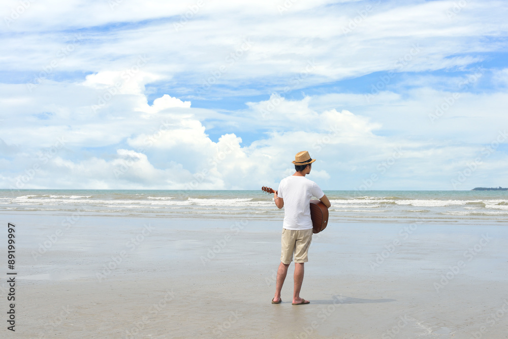 Young man playing an acoustic guitar on the beach