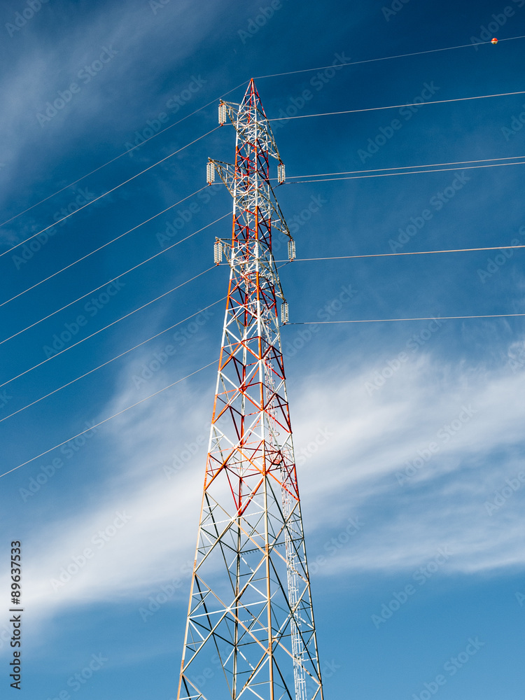 A transmission tower with blue sky and clouds in background