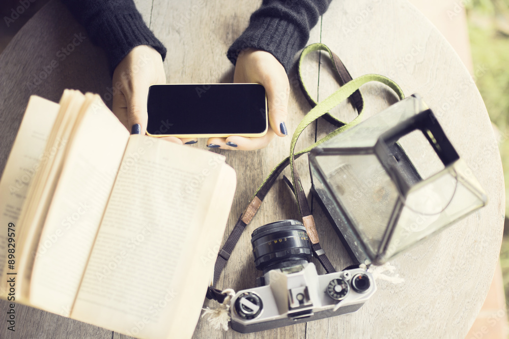 Girl with cell phone, books and old camera