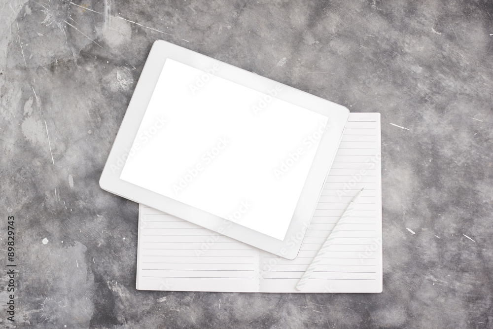 Blank digital tablet and notebook on a concrete background