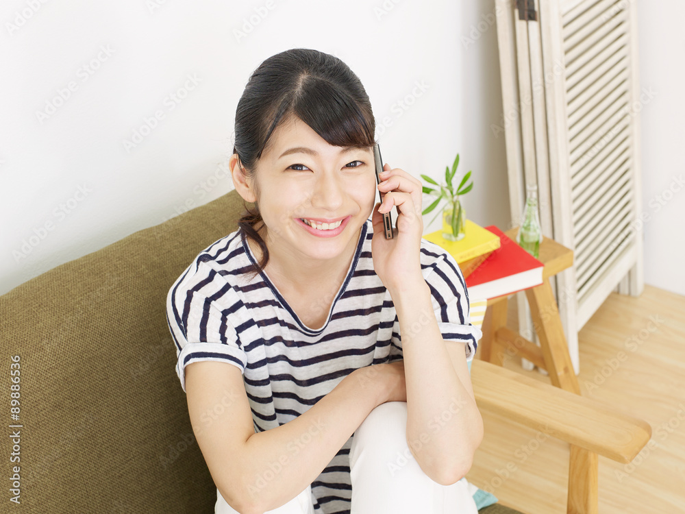 部屋でスマートフォンで話す女性