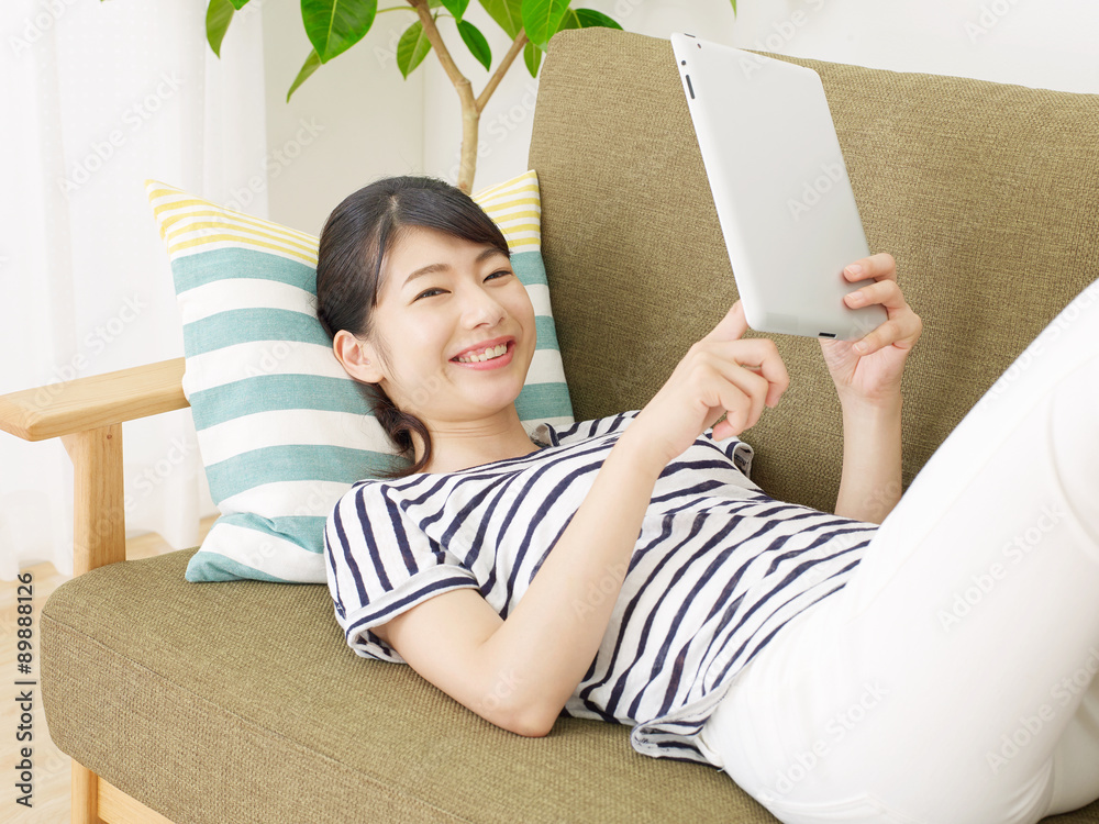 部屋でタブレットを使う女性