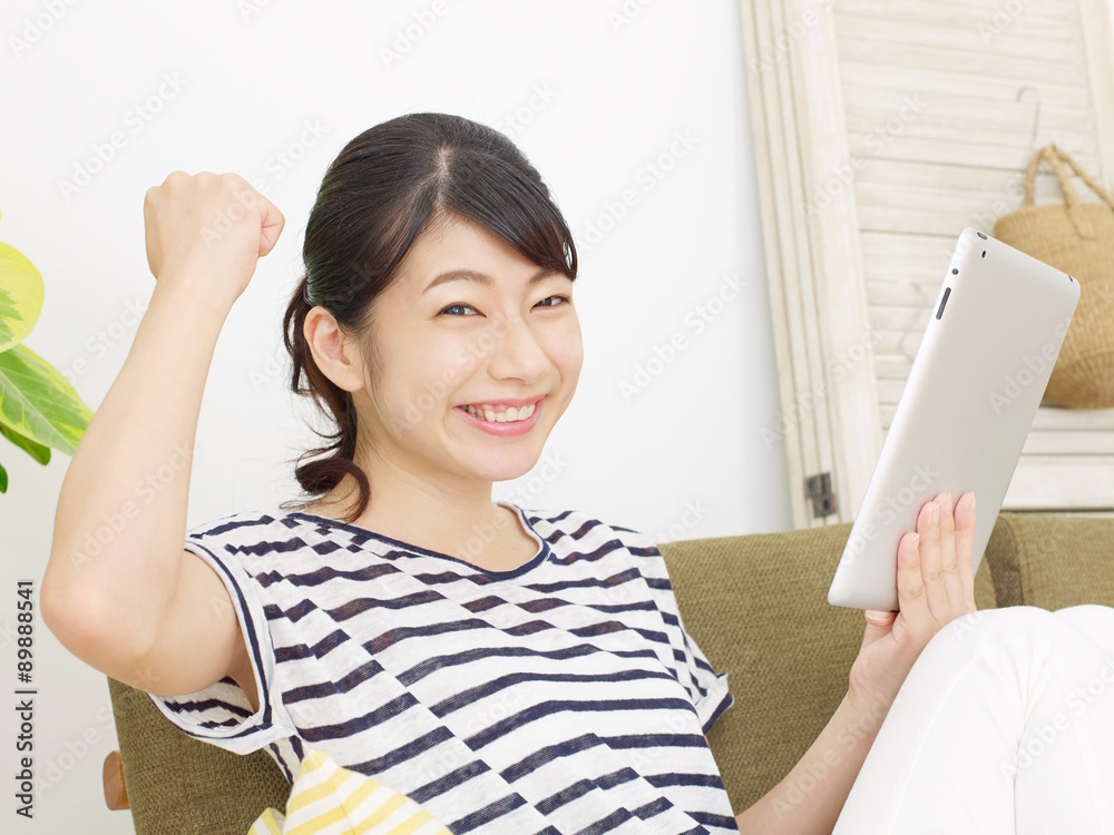 部屋でタブレットを使う女性　ガッツポーズ