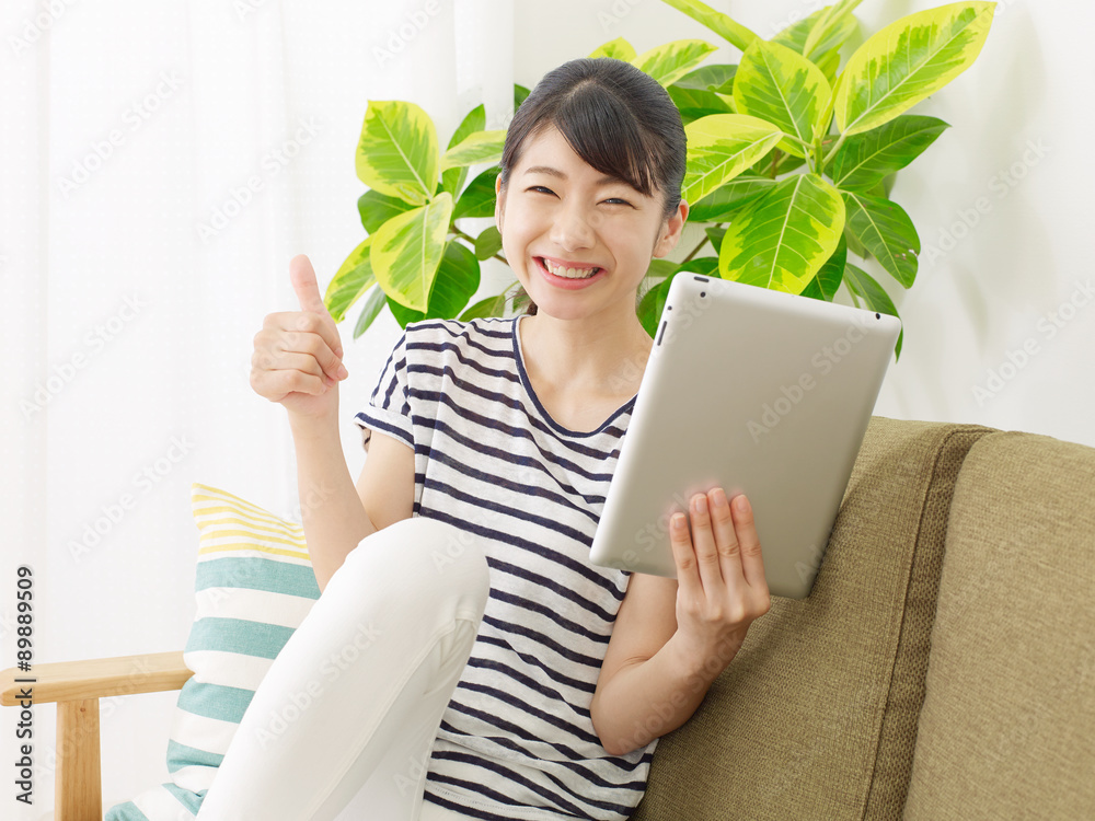 部屋でタブレットを使う女性　グッドサイン