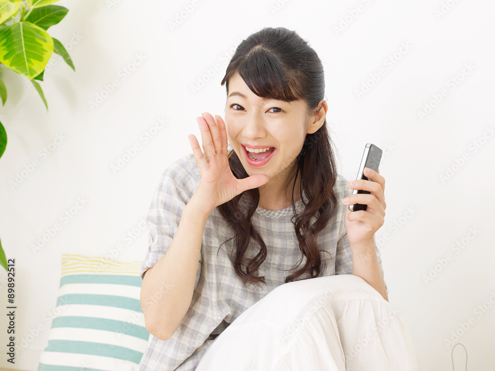 部屋でスマートフォンを持つ女性　呼びかけ