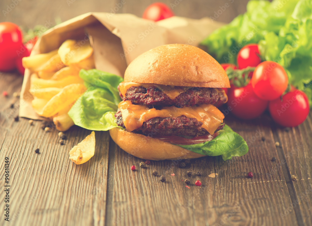 Double cheesburger with fries on wooden table